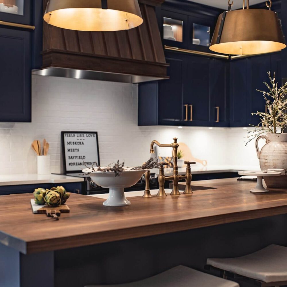 Modern kitchen with navy blue cabinets, wooden island, decorative vase, and pendant lighting.