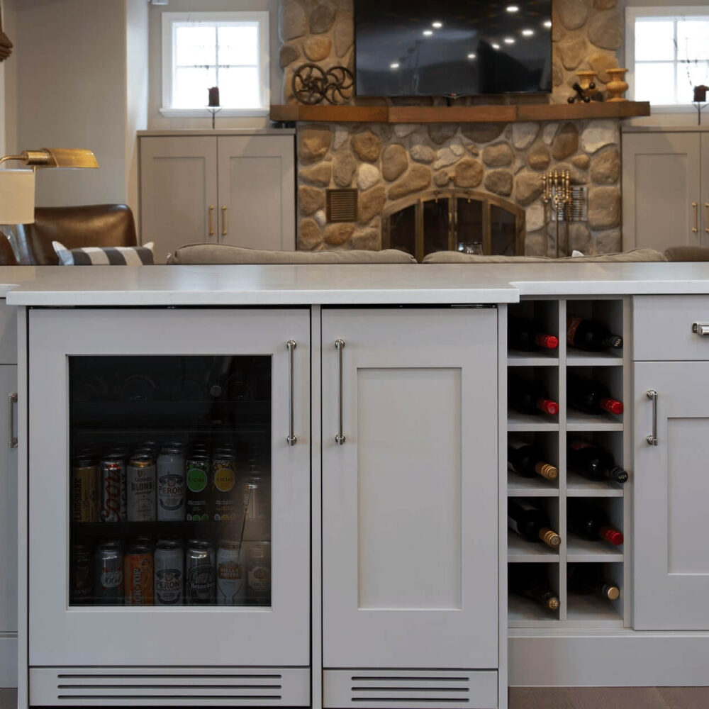 Gray kitchen island with a glass-fronted cabinet for beverages and a wine rack, set in a modern interior design.