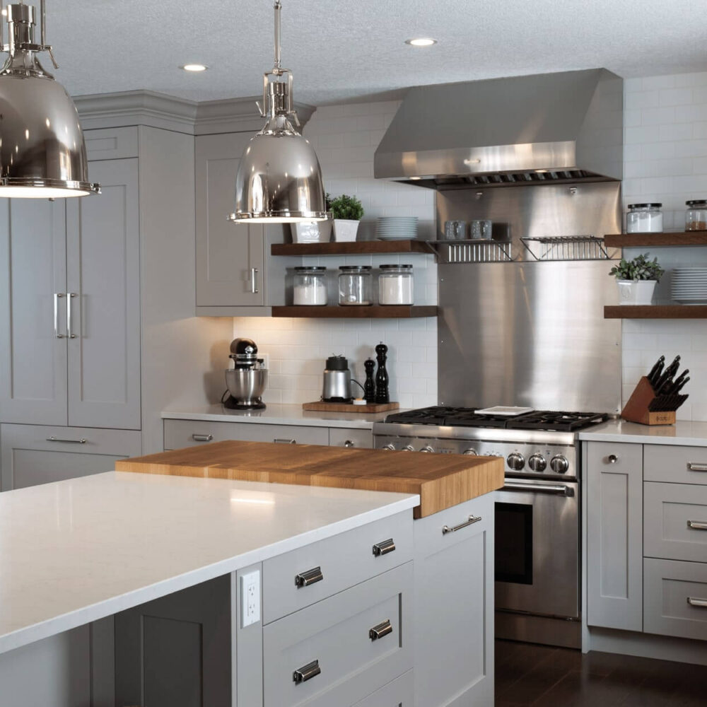 Modern kitchen with gray cabinetry, stainless steel appliances, and a central island featuring a wooden countertop.