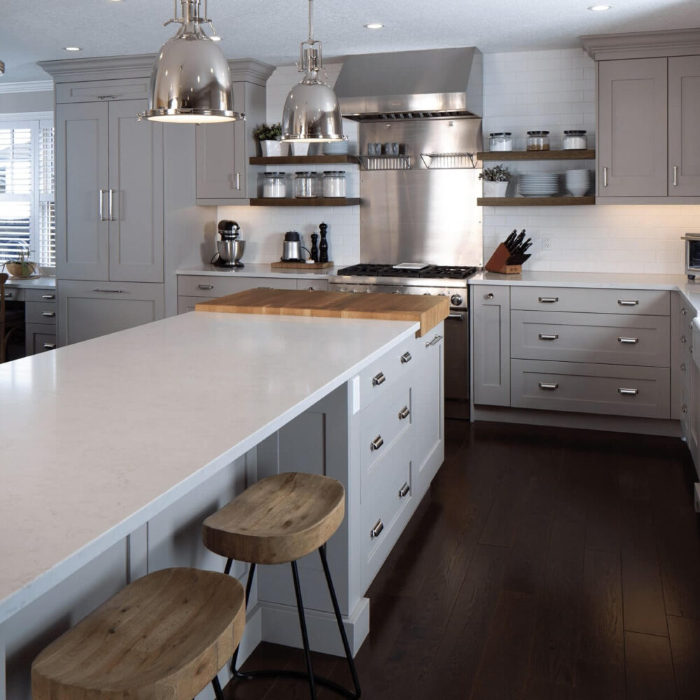 Modern kitchen with gray cabinetry, a large island with a wooden countertop, stainless steel appliances, and pendant lighting.