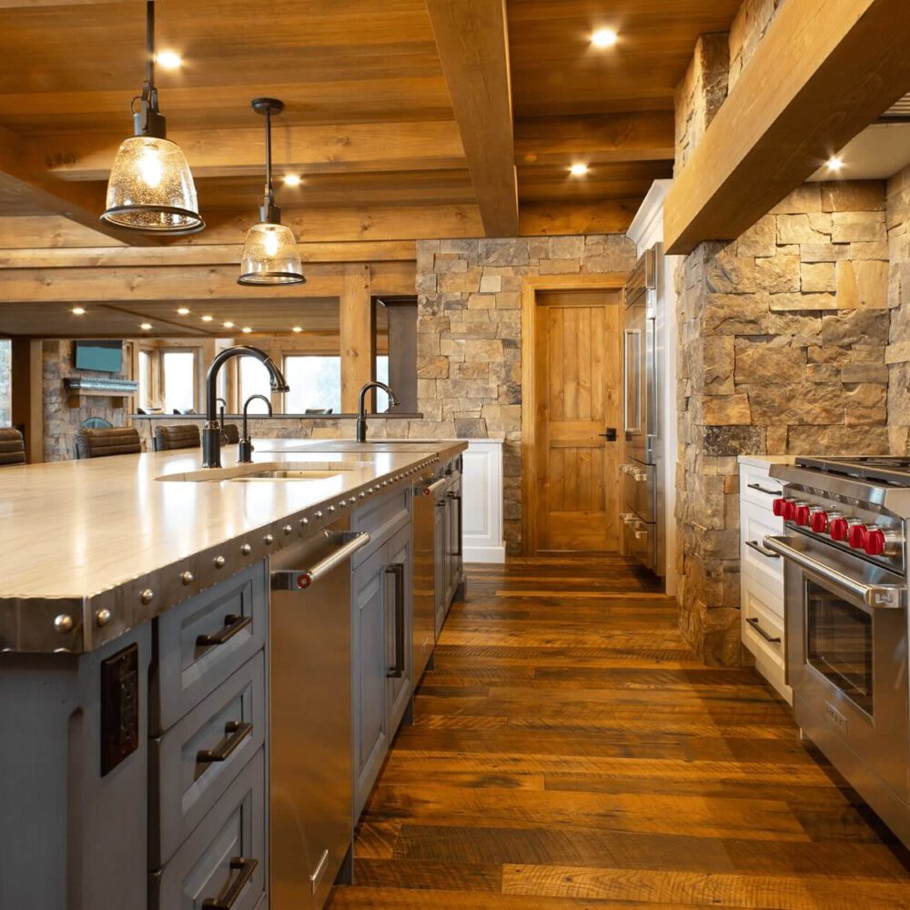 Modern kitchen with a large island, stainless steel appliances, stone accents, and wooden beams in a rustic design.