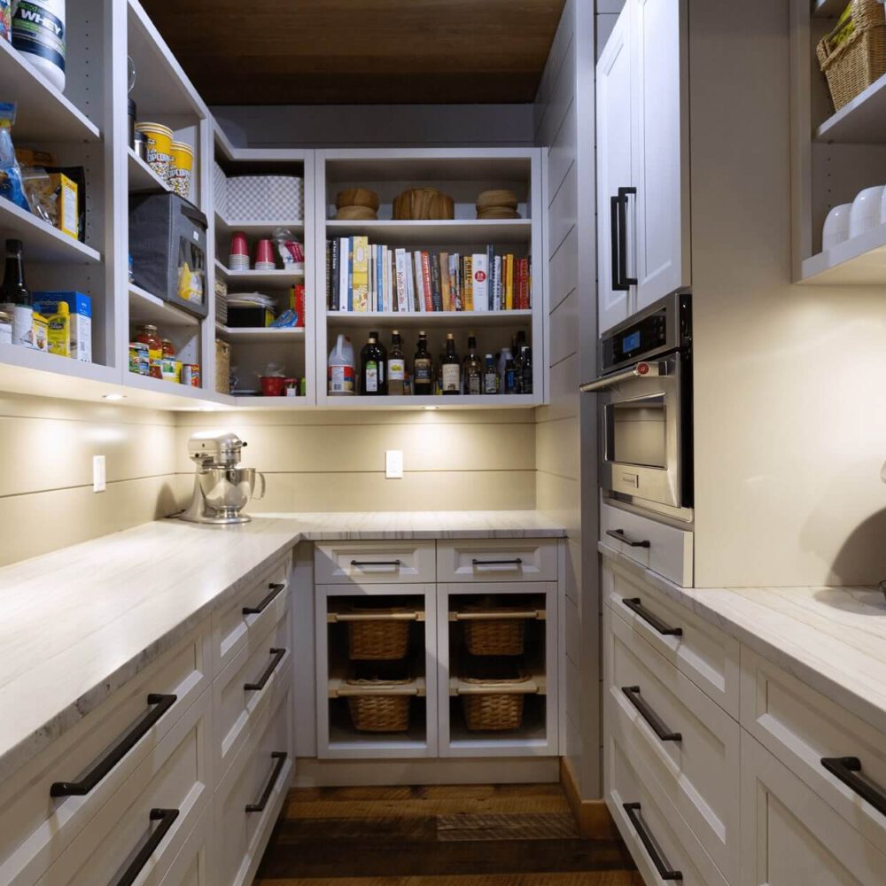 Interior view of a modern kitchen pantry with organized shelves, a countertop, and kitchen appliances including a coffee maker.