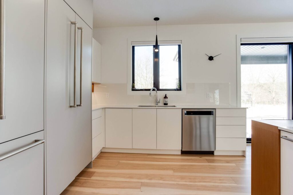 eMg9qin0 Modern kitchen with white cabinetry, stainless steel dishwasher, and large windows providing natural light.