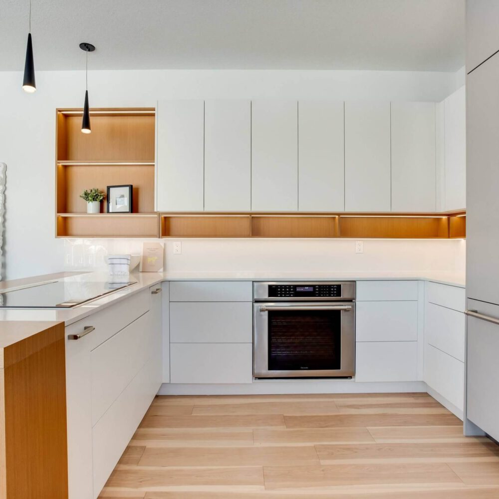 Modern kitchen design featuring white cabinetry, wooden accents, and stainless steel appliances with a minimalist aesthetic.