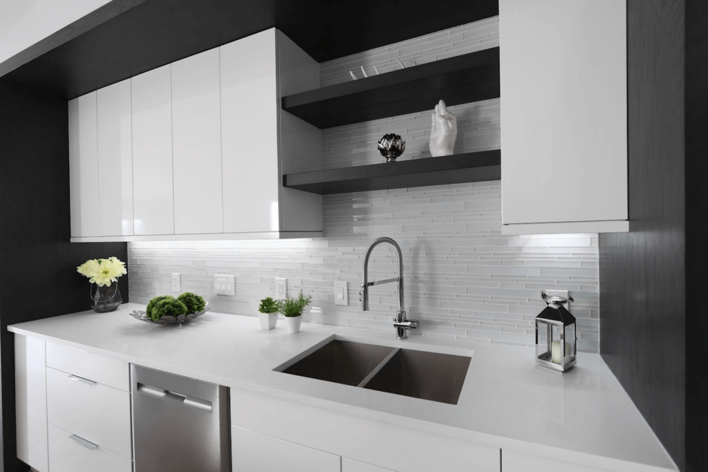 DSC_9983 Modern kitchen design featuring a white countertop, stainless steel sink, and minimalist cabinetry with decorative plants and a lantern.